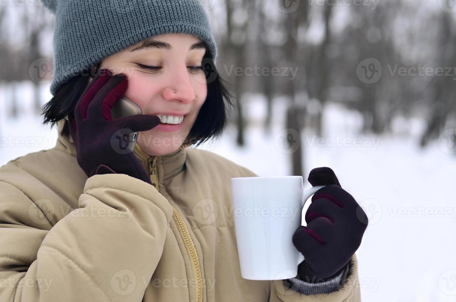 vinter- porträtt av ung flicka med smartphone och kaffe kopp foto