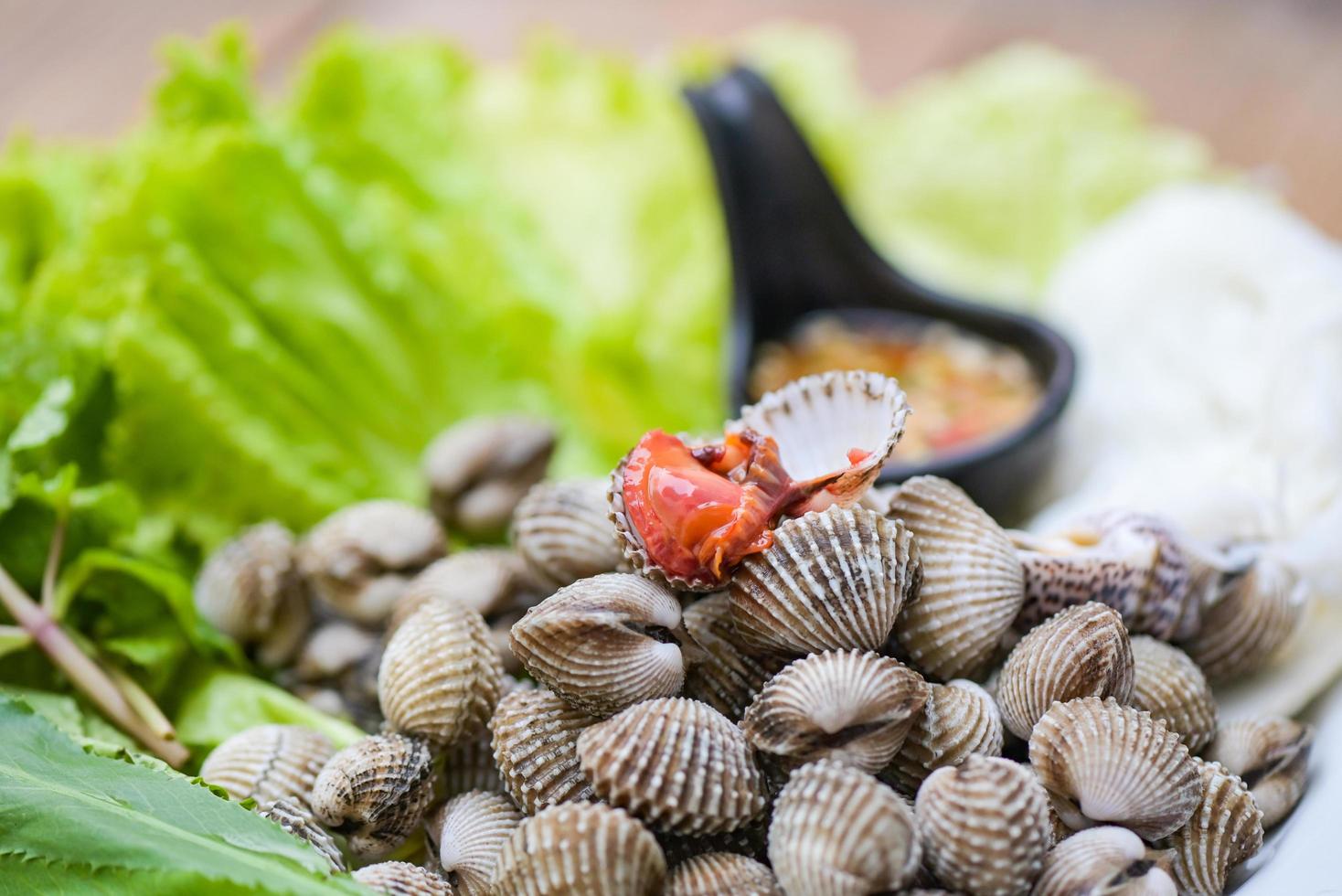 skrynkla skaldjur skaldjur tallrik med färsk vegetabiliska örter och kryddor på tallrik mat hjärtmusslor bakgrund - blod skrynkla skalad på tabell med skaldjur sås foto