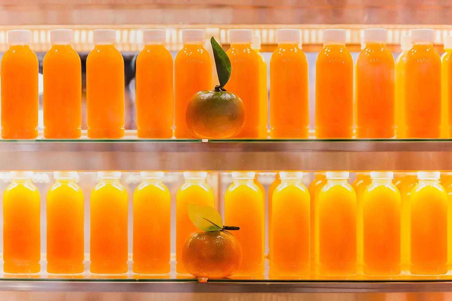 färsk orange juice i flaskor i kylskåp hylla. foto