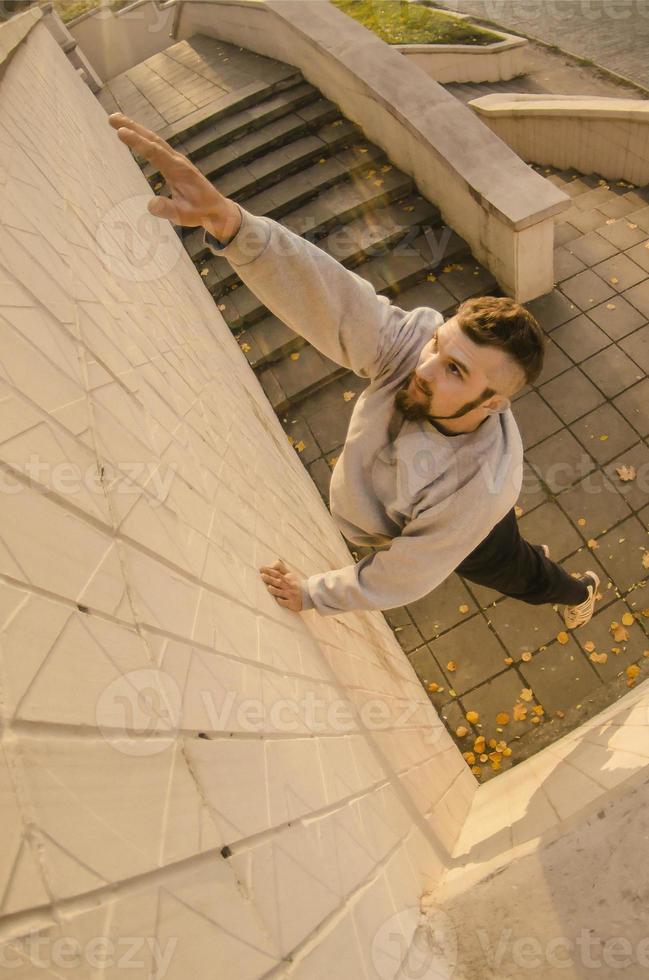 en ung kille övervinner hinder, klättrande på betong väggar. de idrottare praxis parkour, Träning i gata betingelser. de begrepp av sporter subkulturer bland ungdom foto