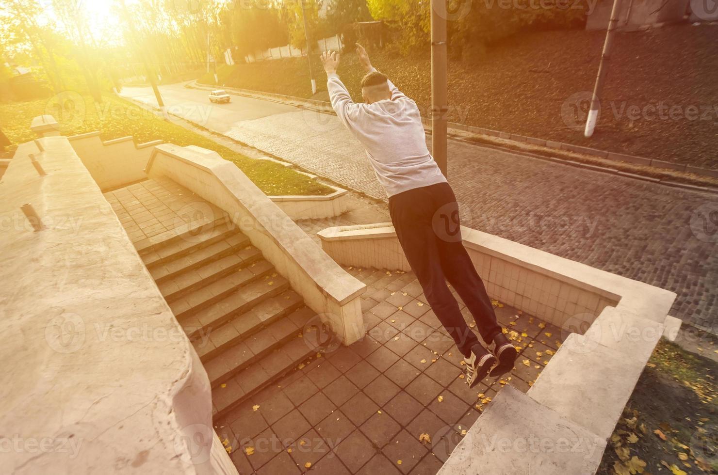 en ung kille utför en hoppa genom de Plats mellan de betong räcken. de idrottare praxis parkour, Träning i gata betingelser. de begrepp av sporter subkulturer bland ungdom foto