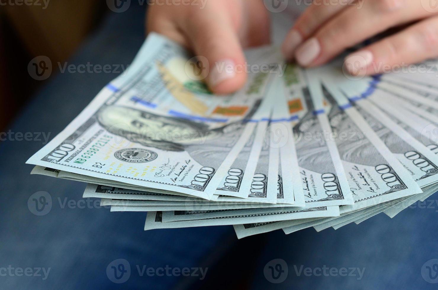 en flicka innehav en fläkt av dollar räkningar foto