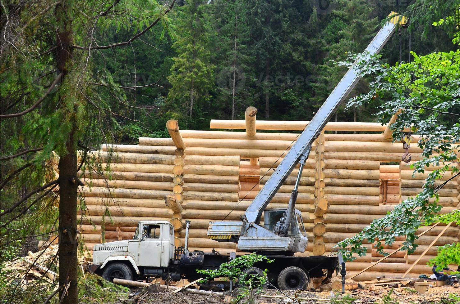 de bearbeta av byggnad en trä- hus från trä- balkar av cylindrisk form. kran i arbetssätt tillstånd foto