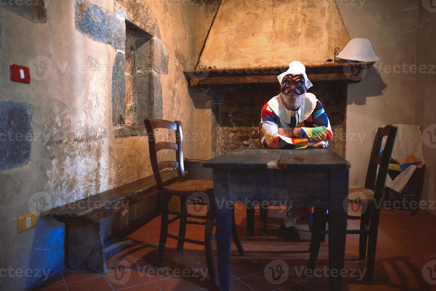 de mask av arlecchino. Sammanträde på de tabell av ett gammal hus foto