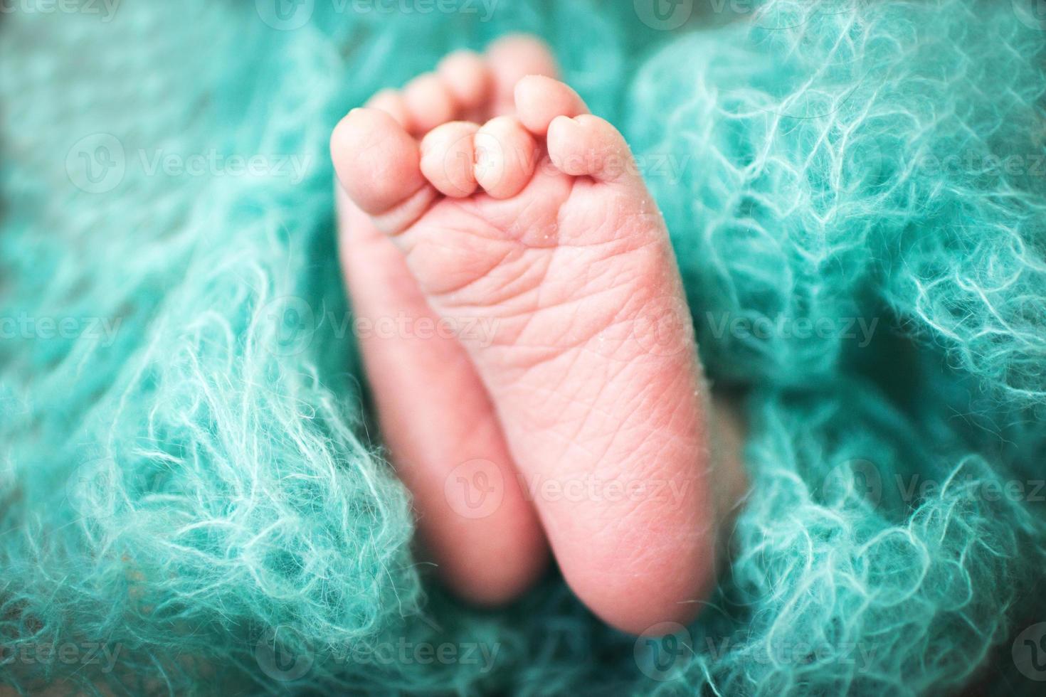 nyfödd bebis fötter. barn ben insvept i en blå filt foto