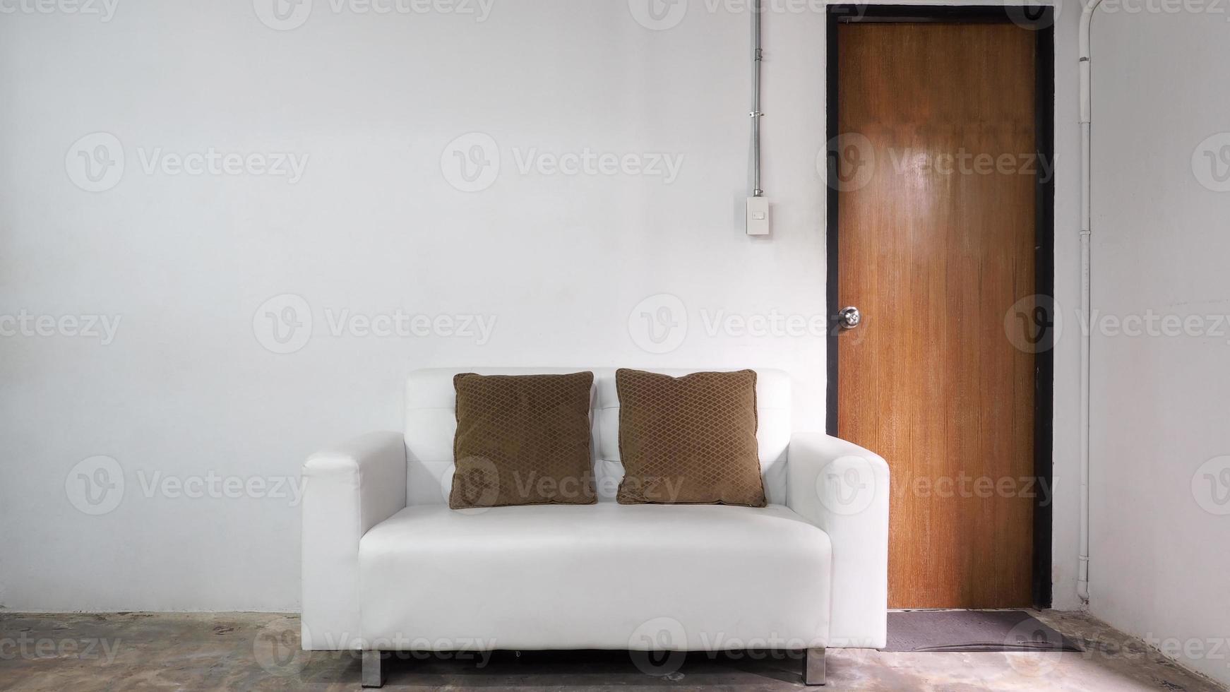 vit läder soffa och vit gammal vägg och gammal trä dörr i rum. foto