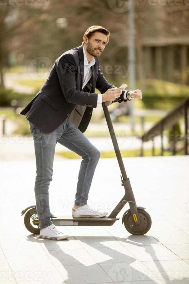 ung affärsman som använder mobiltelefon på elektrisk skoter foto