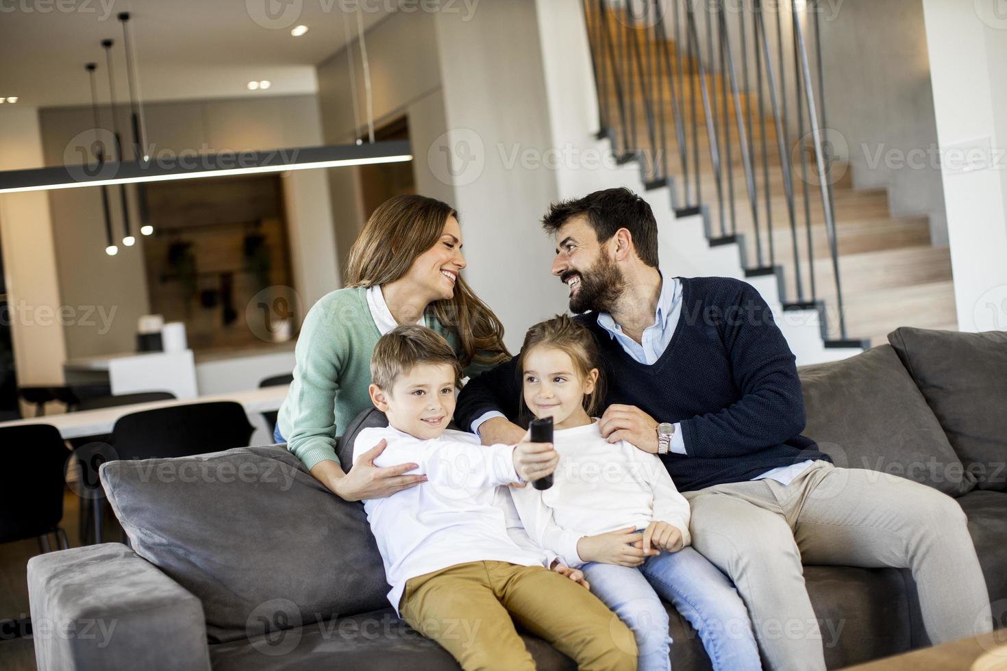 ung familj tittar på TV tillsammans på de soffa i de levande rum foto
