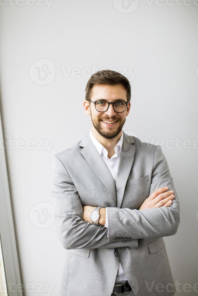 ung modern affärsman stående förbi de vägg i de kontor foto