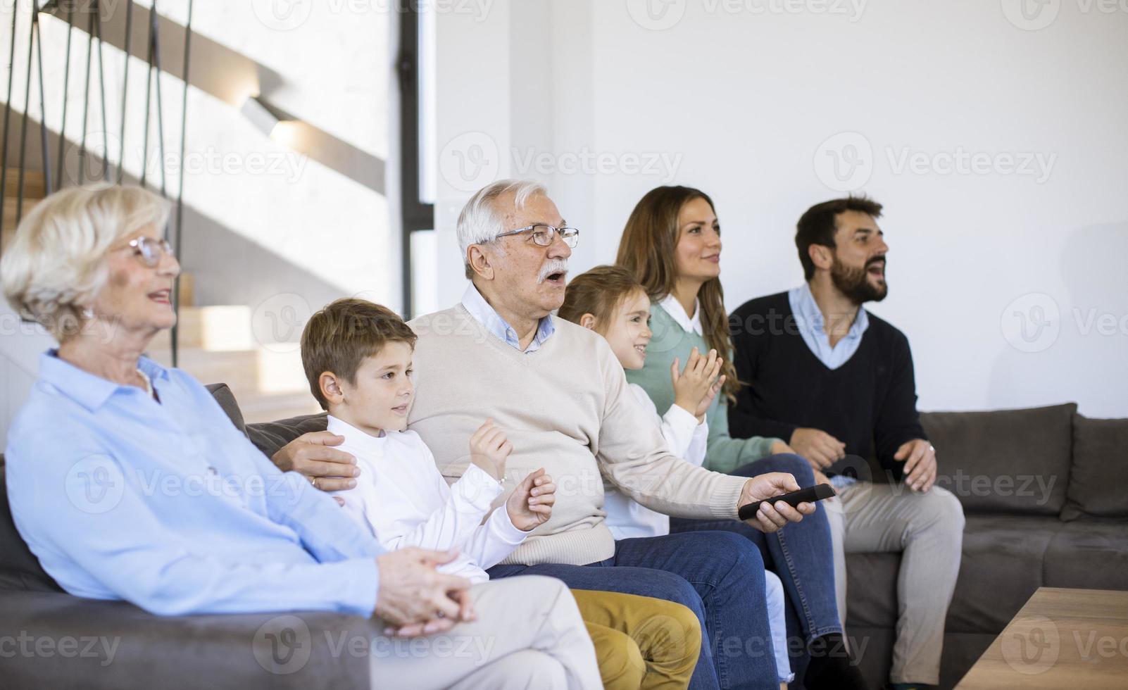 mång generation familj Sammanträde tillsammans på de soffa på Hem och tittar på TV foto