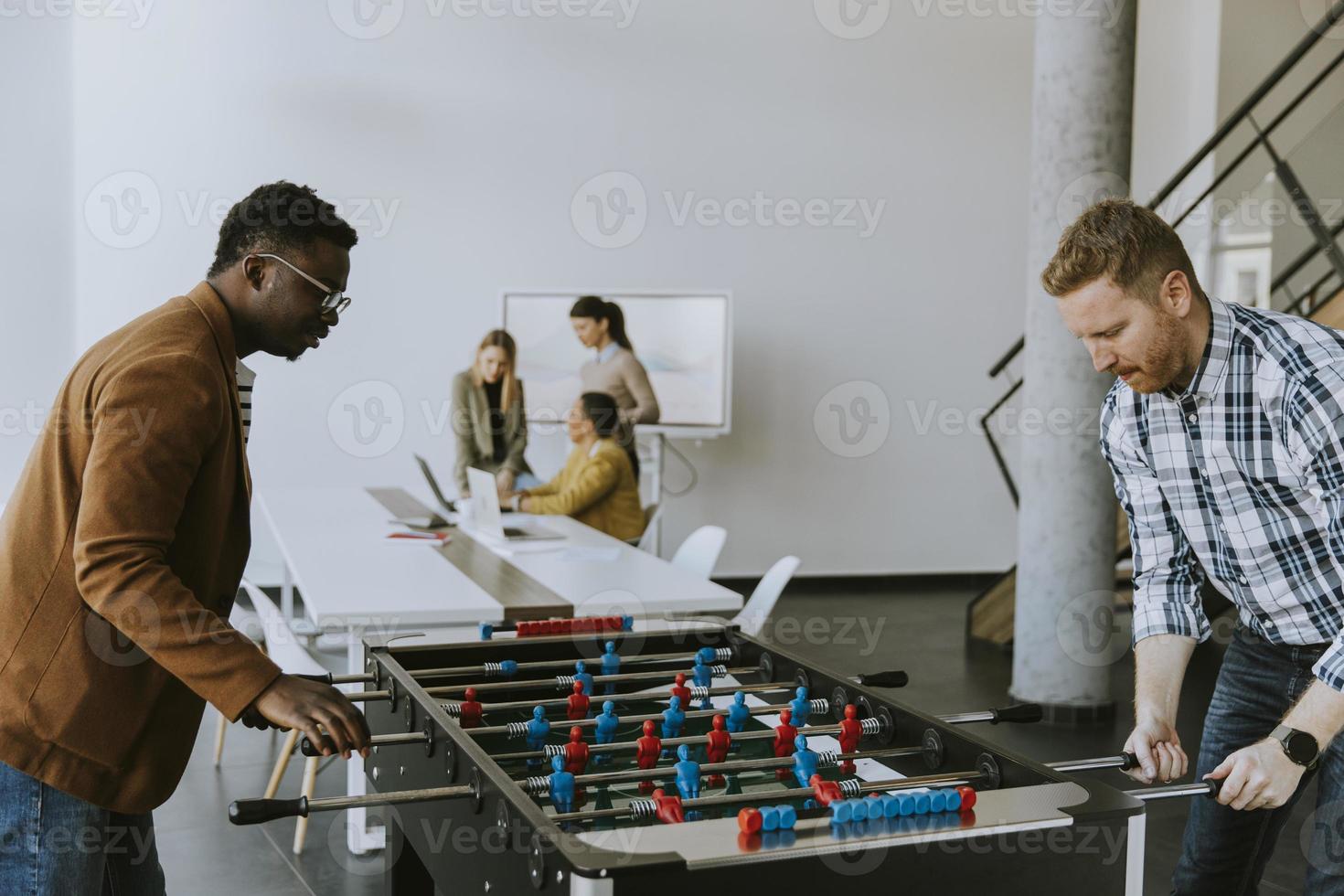 ung tillfällig multietnisk företag människor spelar tabell fotboll och avkopplande på kontor foto