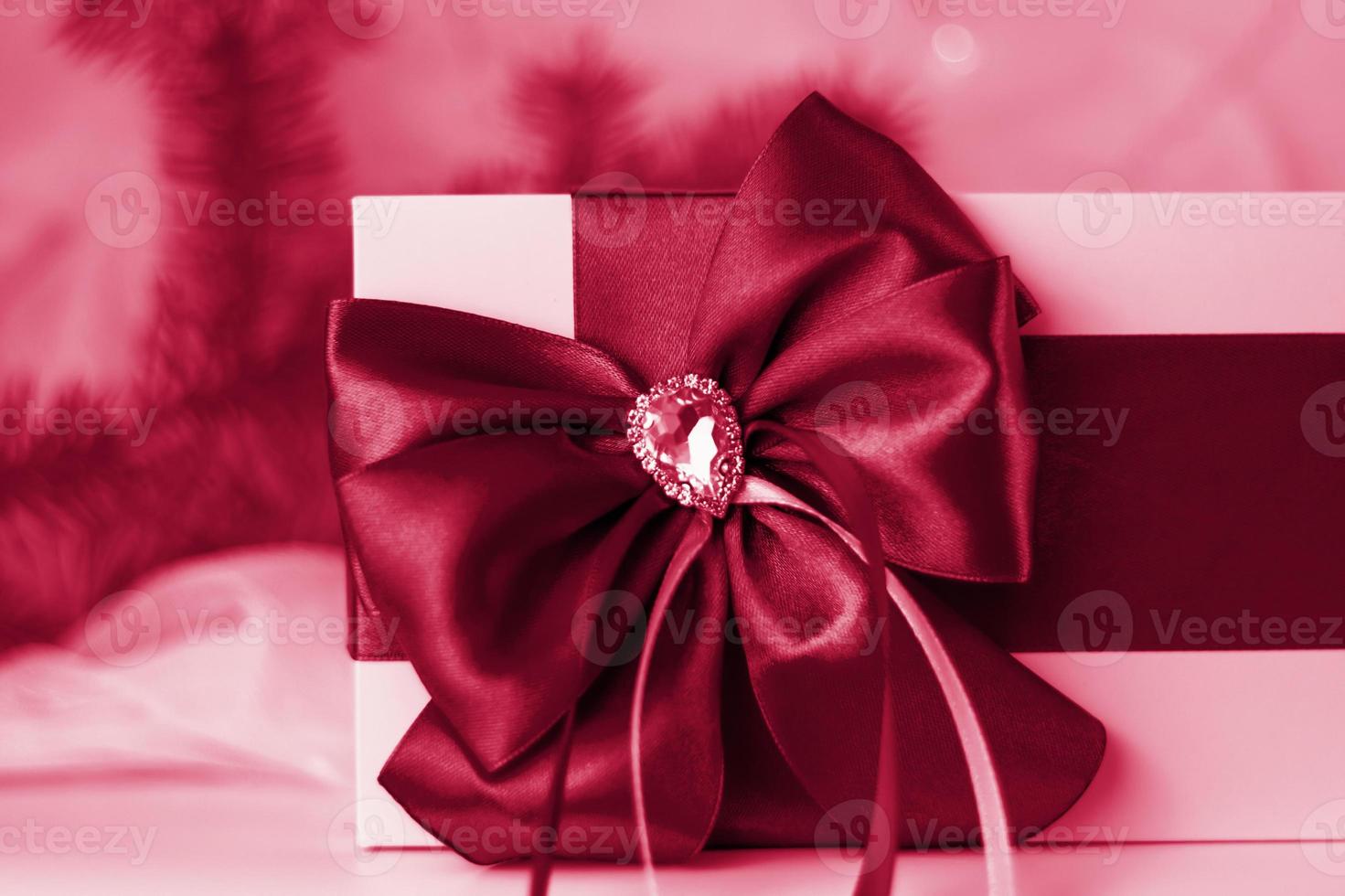 en jul gåva dekorerad med en skön rosett på en ljus bakgrund med en gran kvist. gåvor, glädje, överraskning. selektiv fokus. de begrepp av jul och ny år. foto