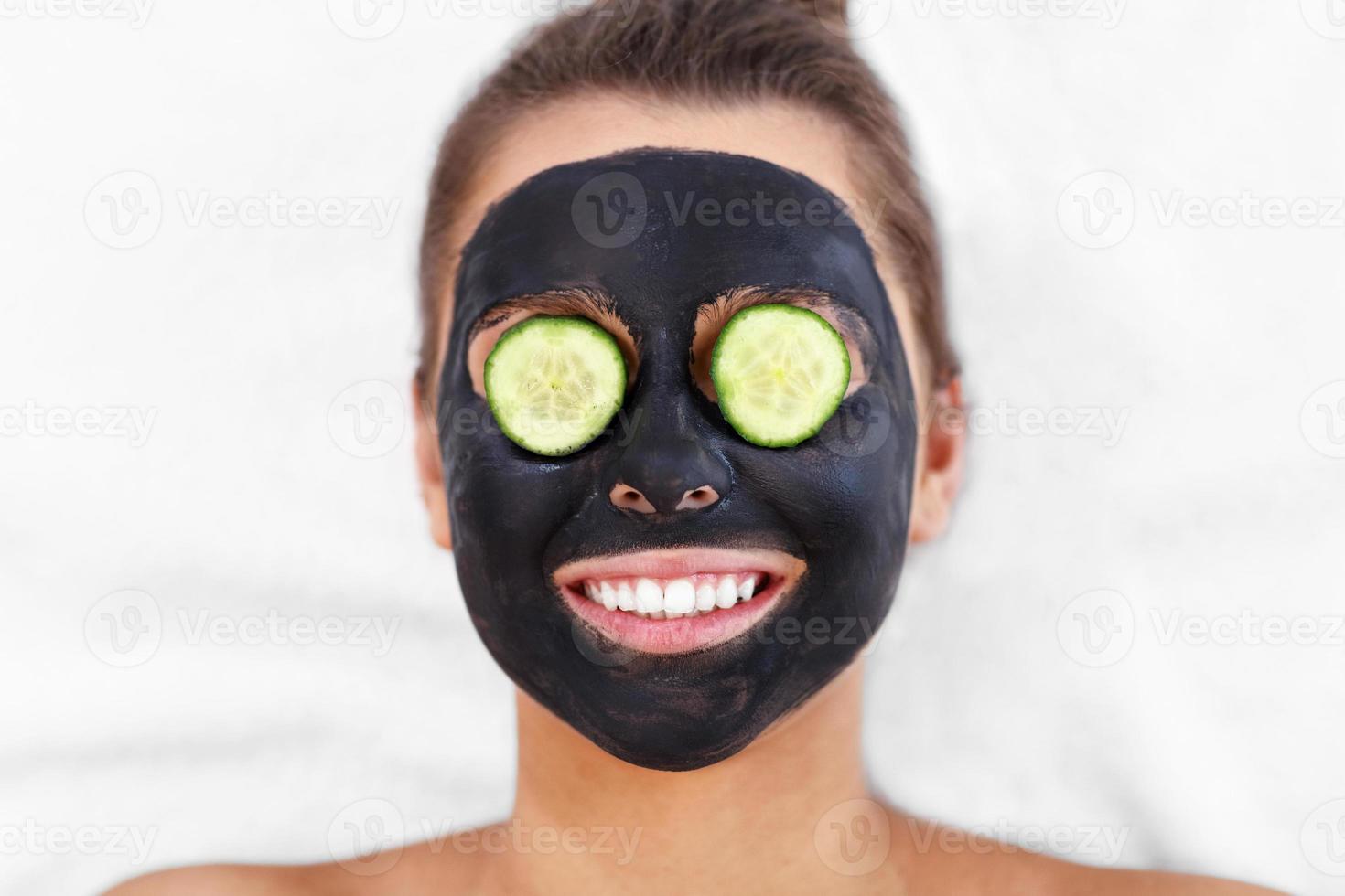 Lycklig kvinna har ansiktsbehandling i spa salong foto