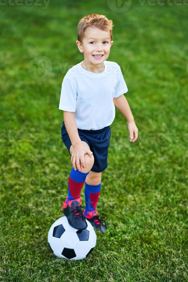 liten pojke praktiserande fotboll utomhus foto