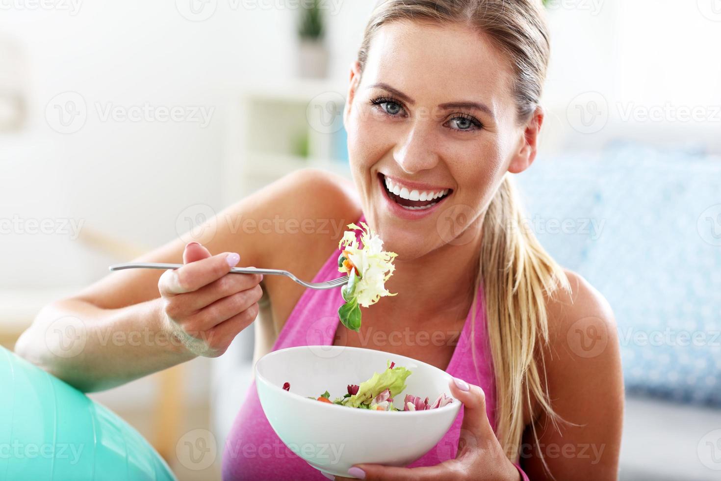 ung kvinna äter friska sallad efter träna foto