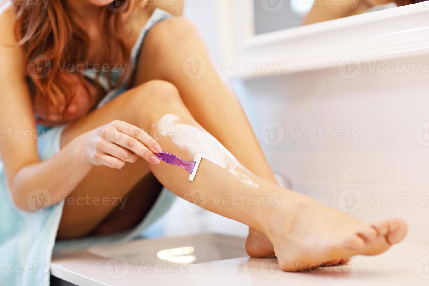 ung kvinna rakning ben i badrum i de morgon- foto