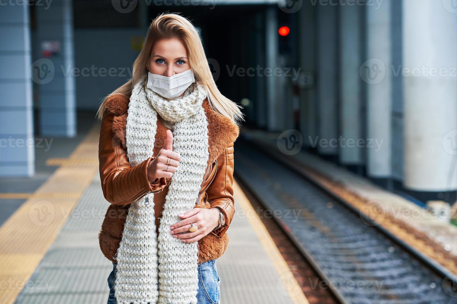 vuxen kvinna på tåg station bär masker på grund av till covid-19 restriktioner foto