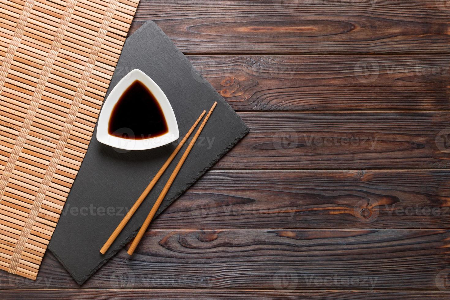 ätpinnar och soja sås på svart sten tallrik, trä- bakgrund med kopia Plats foto