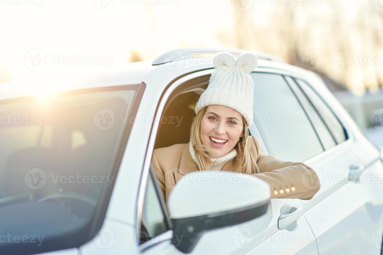 Lycklig kvinna körning bil i snöig vinter- foto