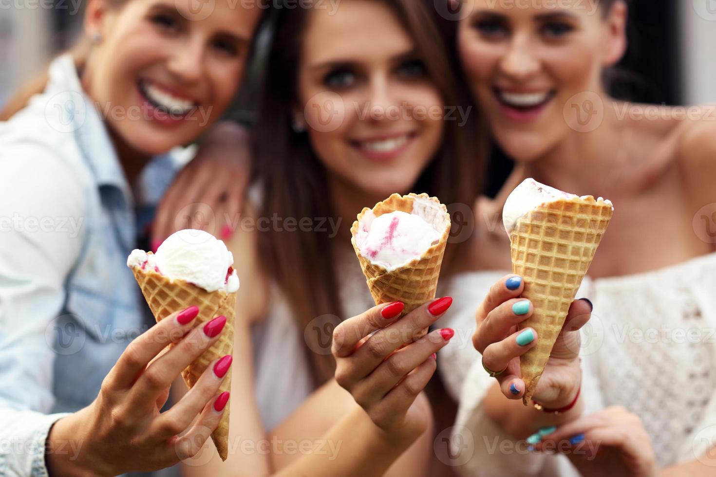 Lycklig grupp av vänner äter glass utomhus foto