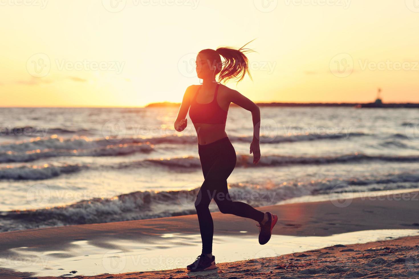 kvinna löpning ensam på skön skymning på de strand foto