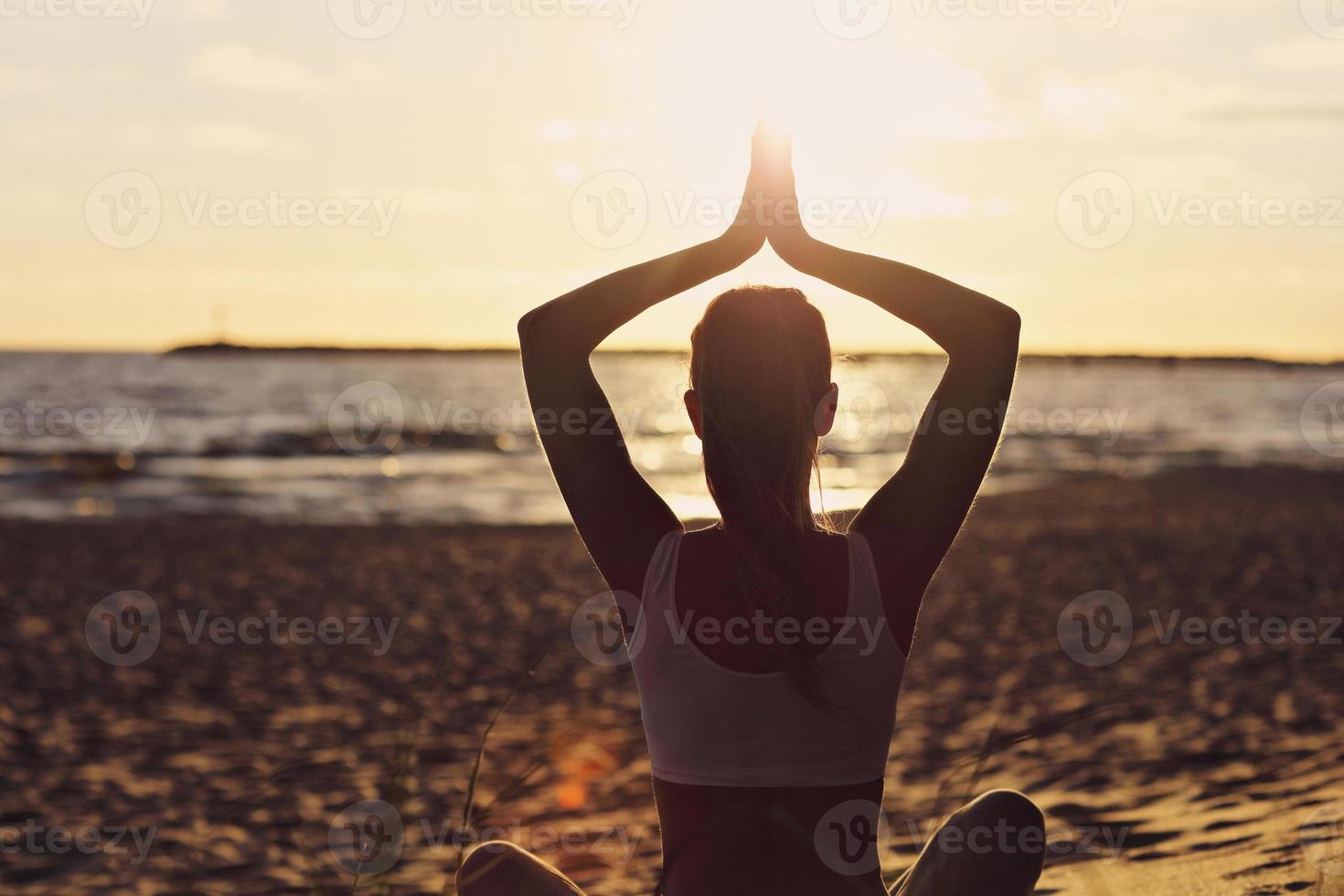 silhuett ung kvinna öva yoga på stranden vid solnedgången foto