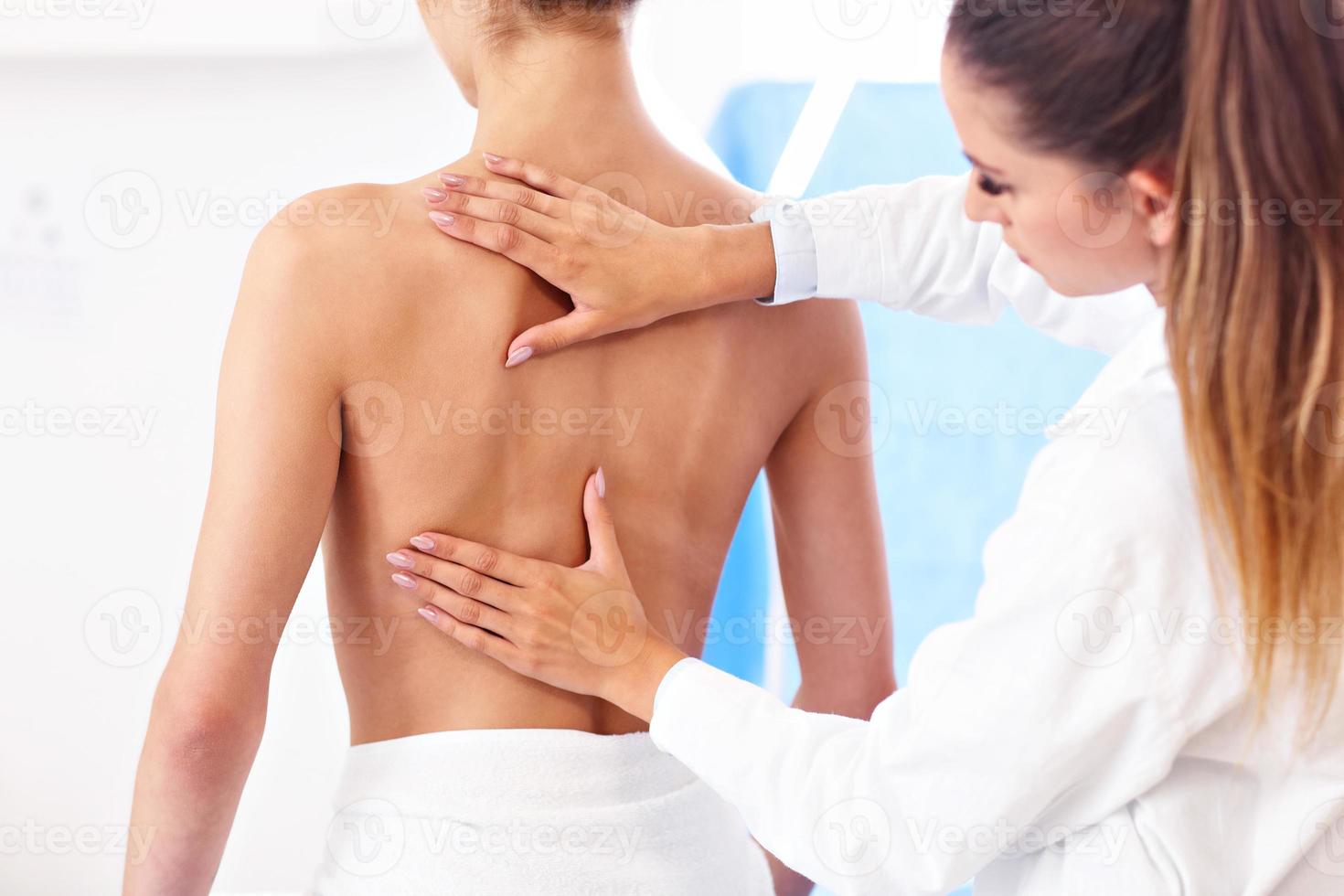 kvinna fysioterapeut portion en patient med tillbaka problem i klinik foto