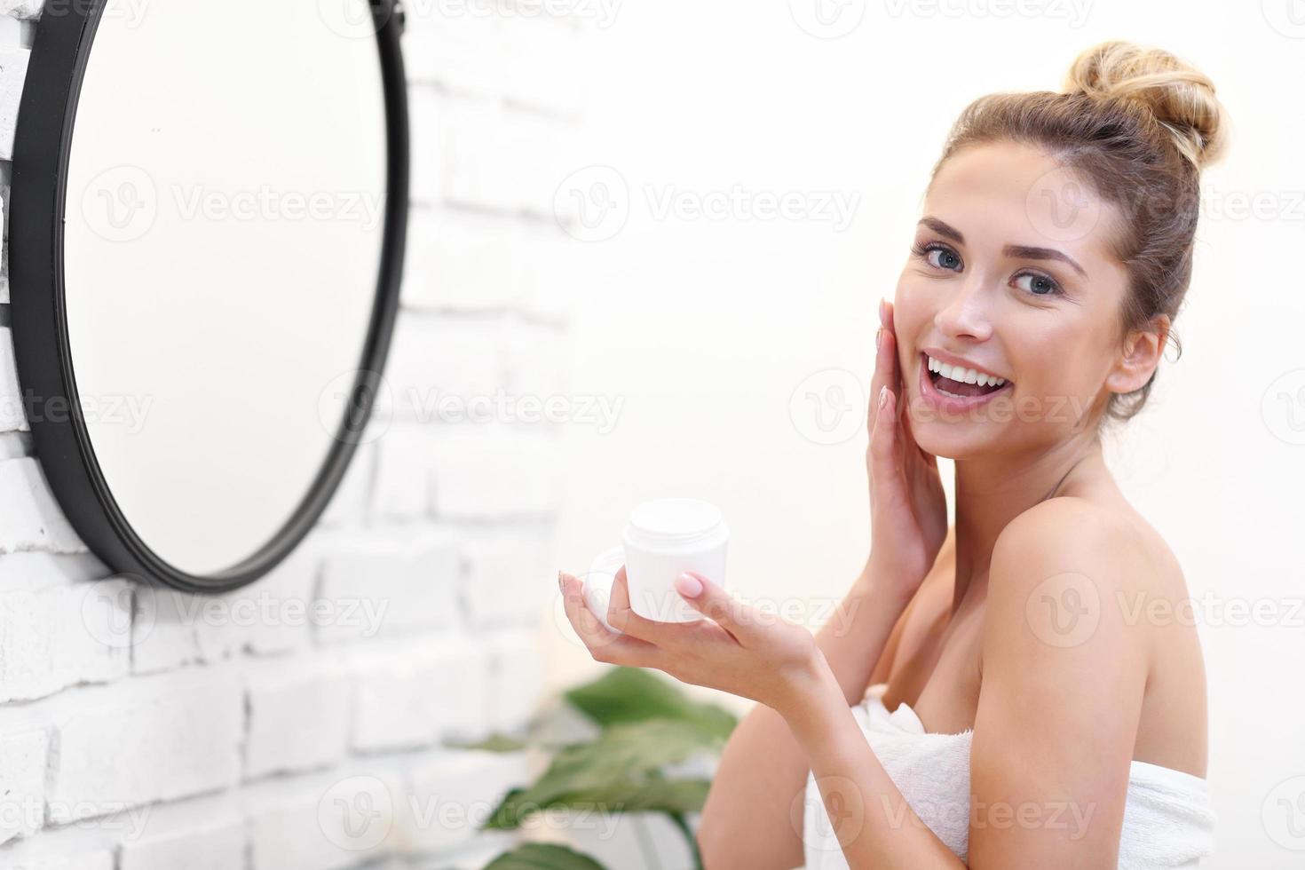 ung kvinna rengöring ansikte i badrum spegel foto
