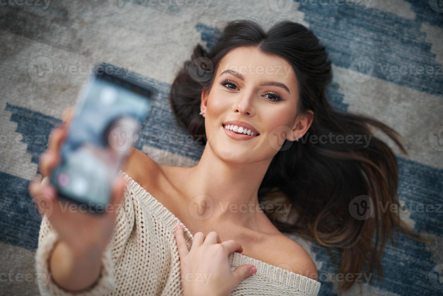 ung sexig kvinna avkopplande på Hem använder sig av smartphone foto