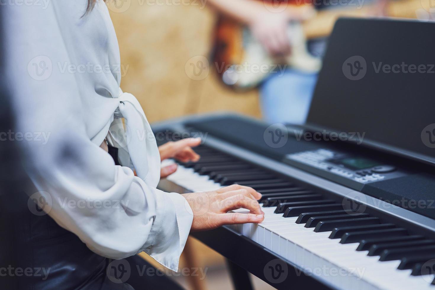 caucasian kvinna spelar på tangentbord med band foto