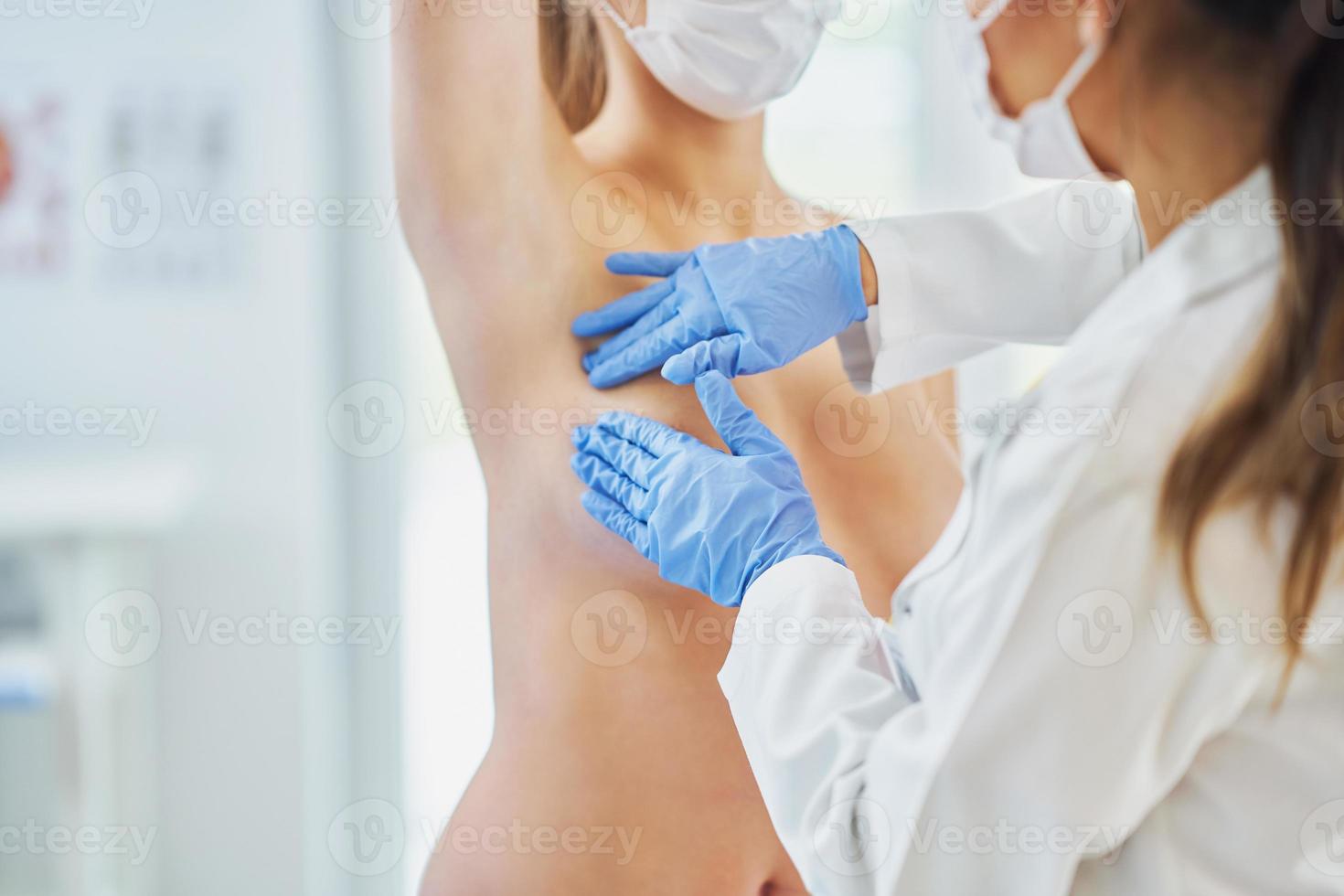 läkare i mask kontroll upp bröst till henne patient foto