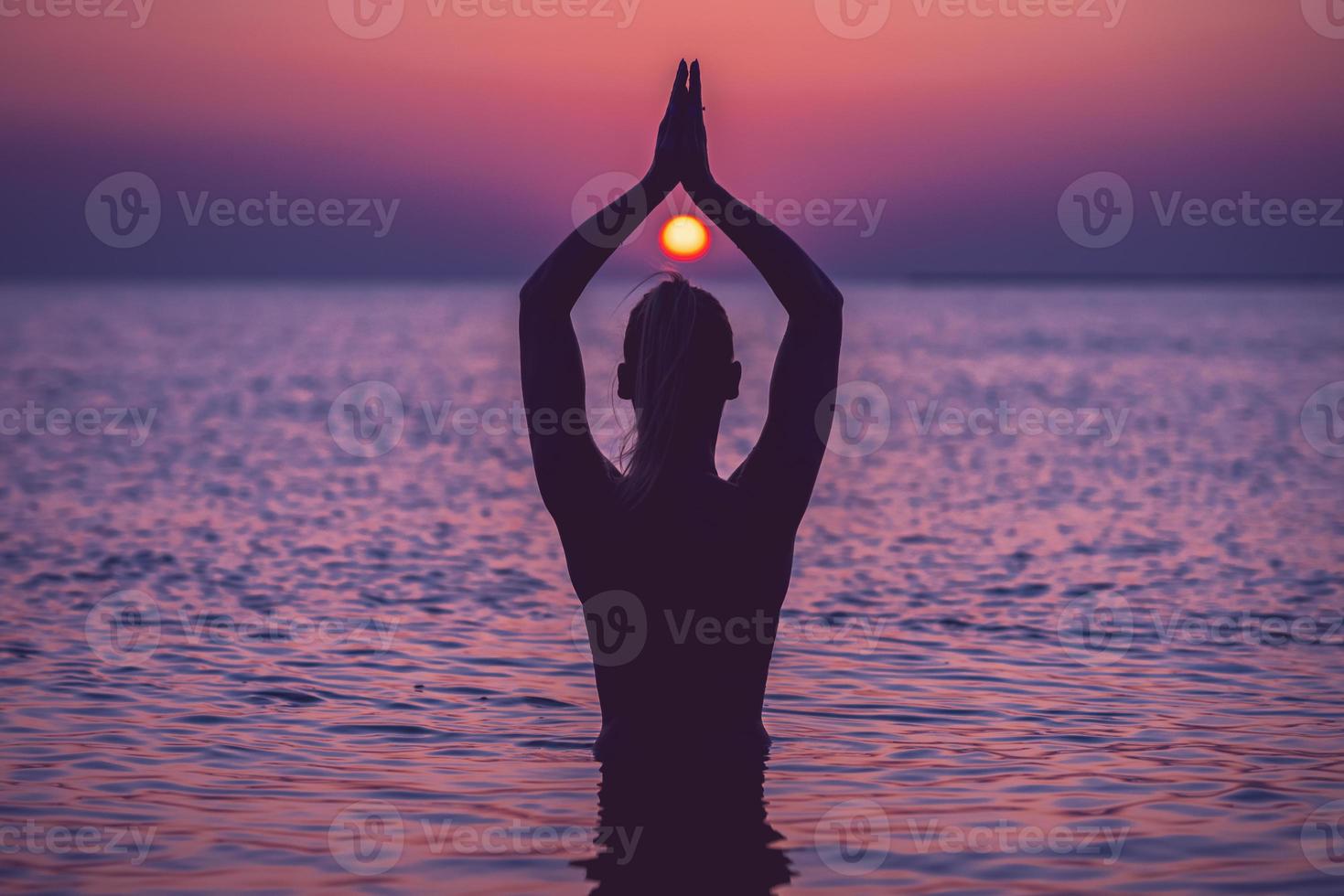 silhuett av ung kvinna praktiserande yoga på de strand på soluppgång foto