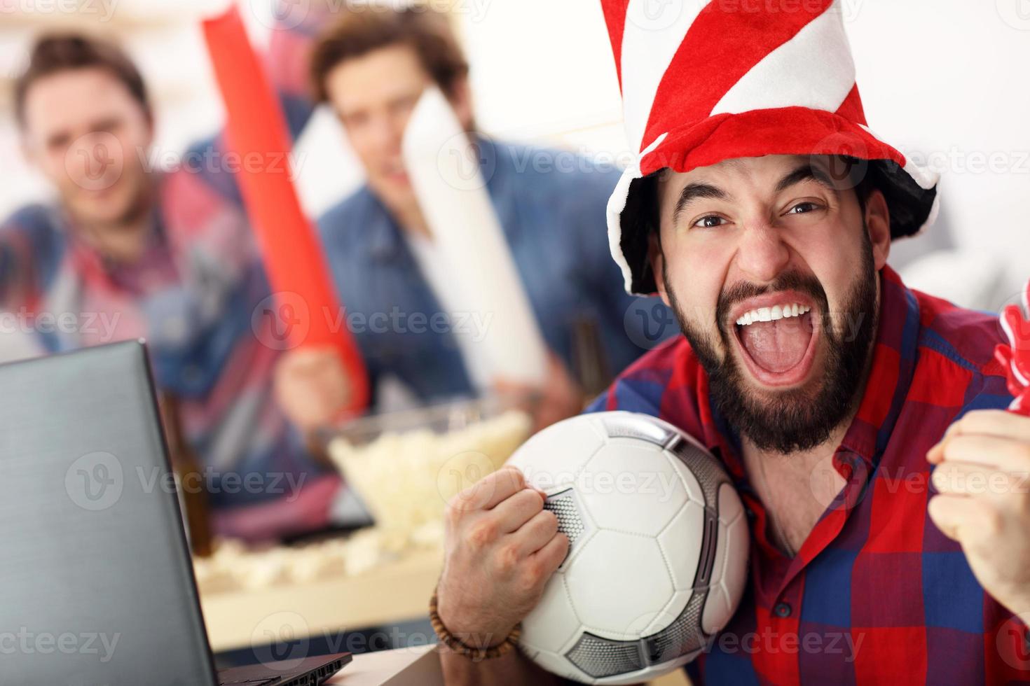 Lycklig manlig vänner glädjande och tittar på sporter på TV foto
