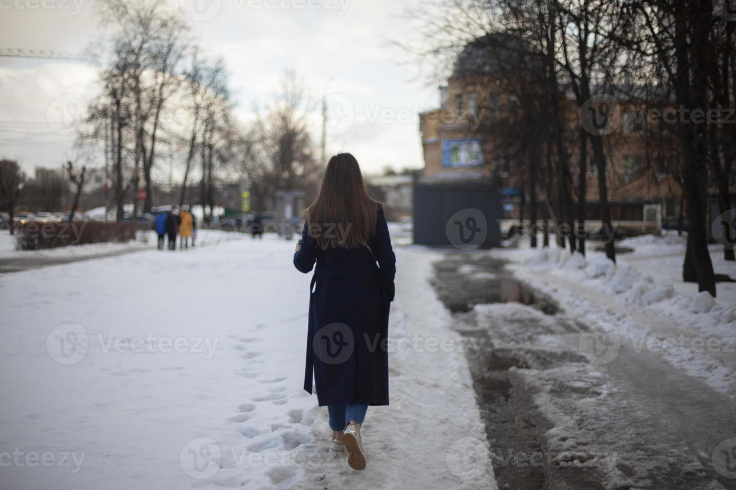 flicka promenader ner gata i vinter. kvinna i vinter- i stad. dålig väg i gård i Ryssland. foto