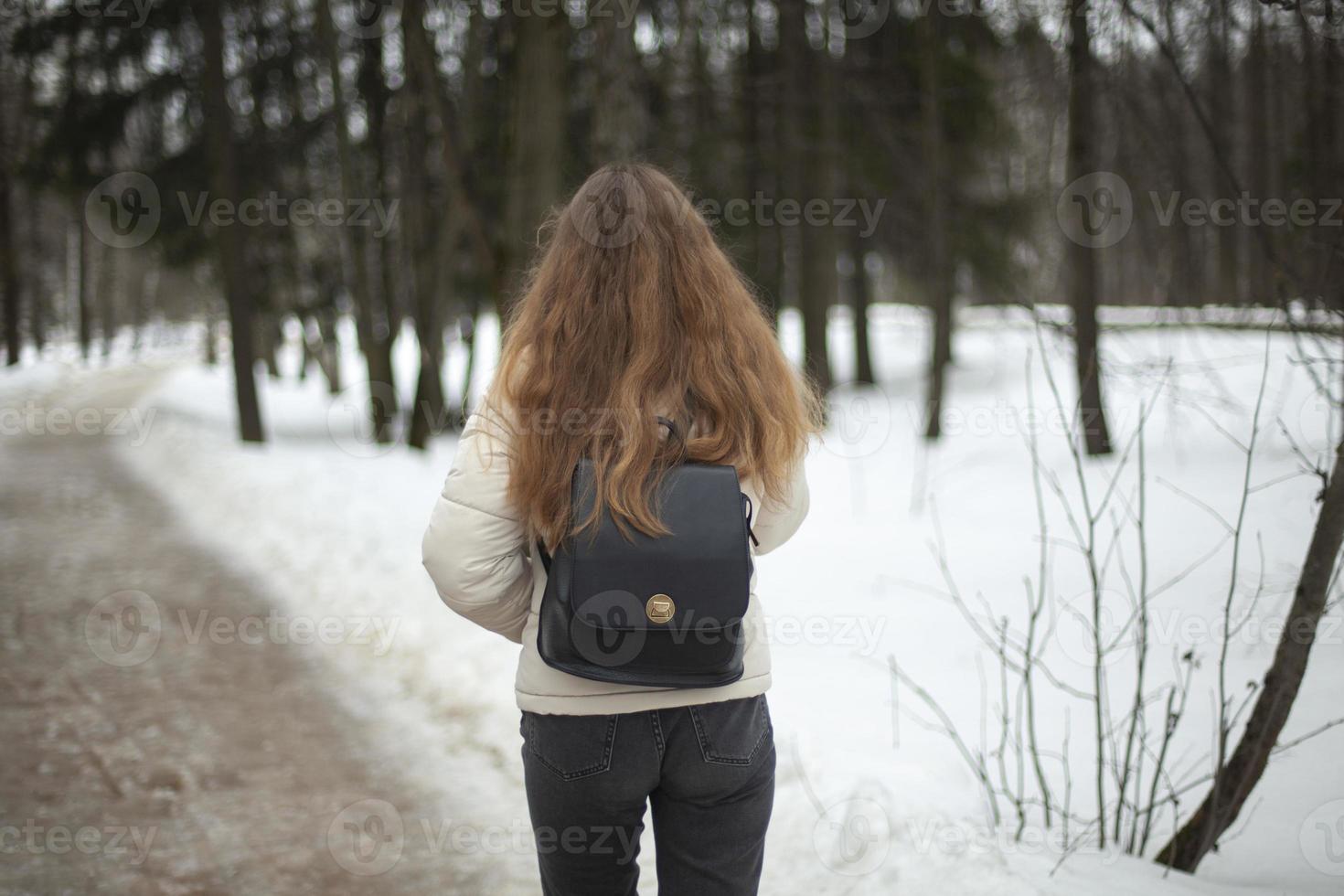 flicka promenader ner gata i vinter. kvinna i vinter- i stad. dålig väg i gård i Ryssland. foto