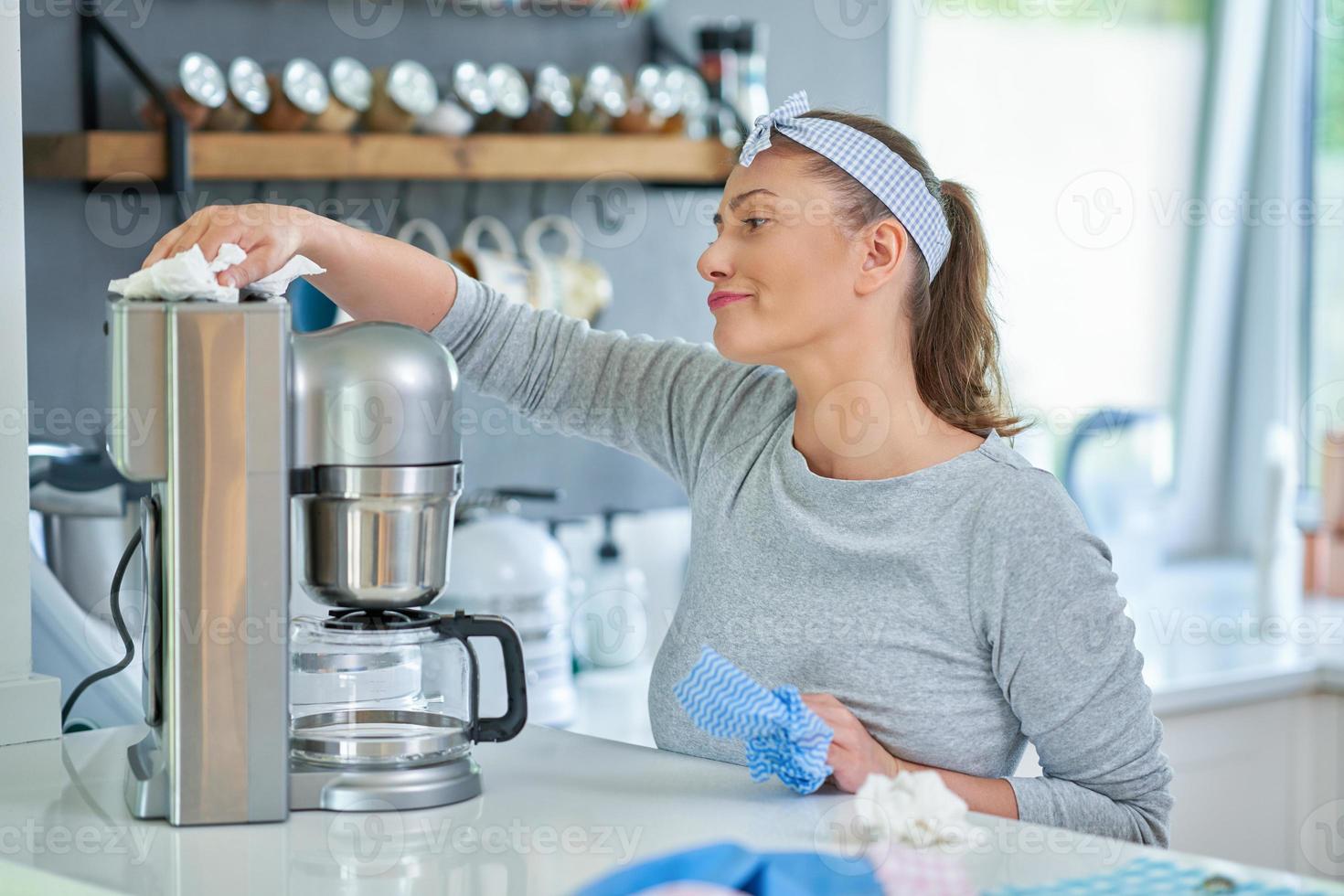 ung kvinna rengöring kaffe pott eller maskin foto