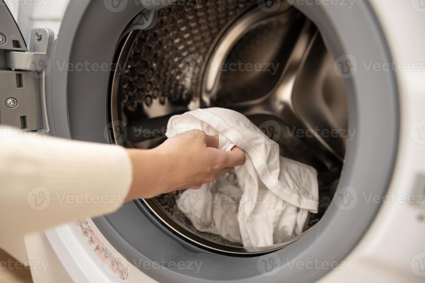 närbild kvinna hand är förvaring kläder i tvättning maskin , hälsa vård livsstil begrepp foto