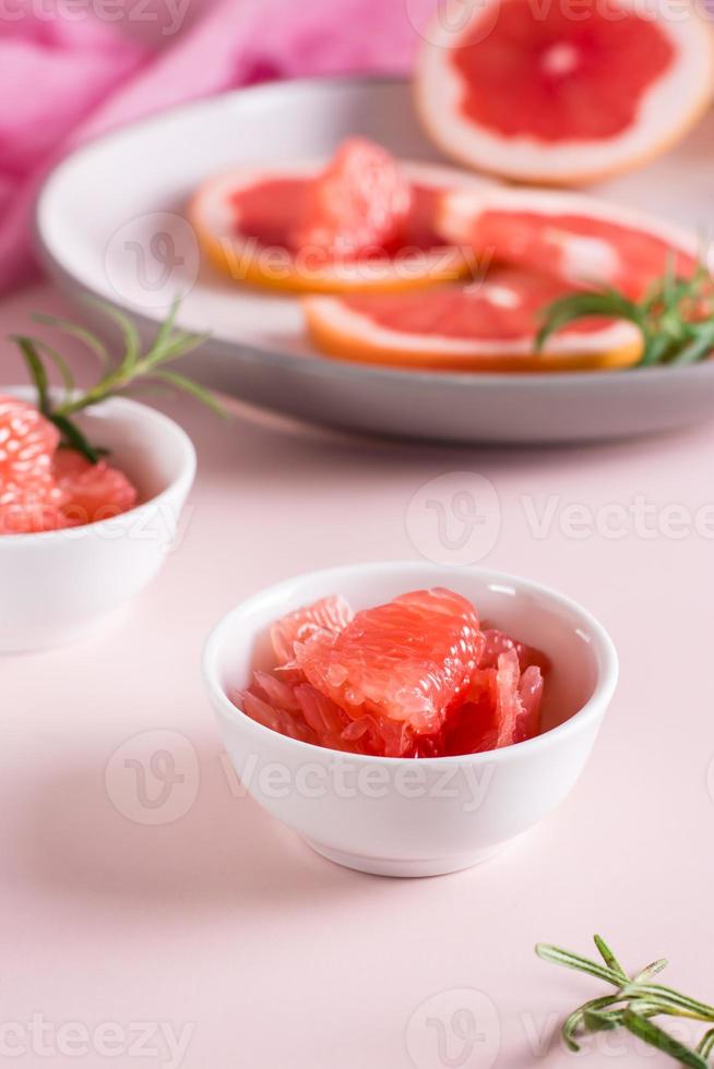 skalad bitar av grapefrukt och rosmarin i en skål på de tabell. cocktail Ingredienser. vertikal se foto