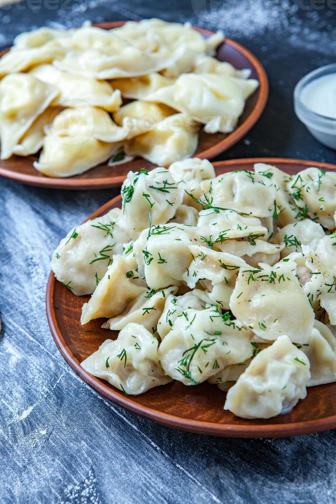 traditionell ryska pelmeni eller ravioli, klimpar med kött på trä svart bakgrund. ryska mat och ryska kök begrepp. foto