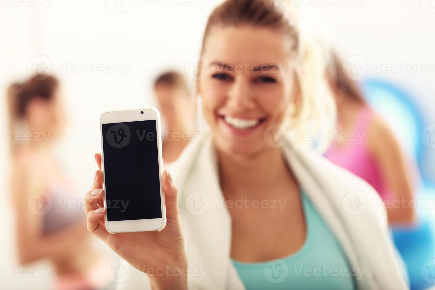 porträtt av skön mogna kvinna med smartphone leende i hälsa klubb foto