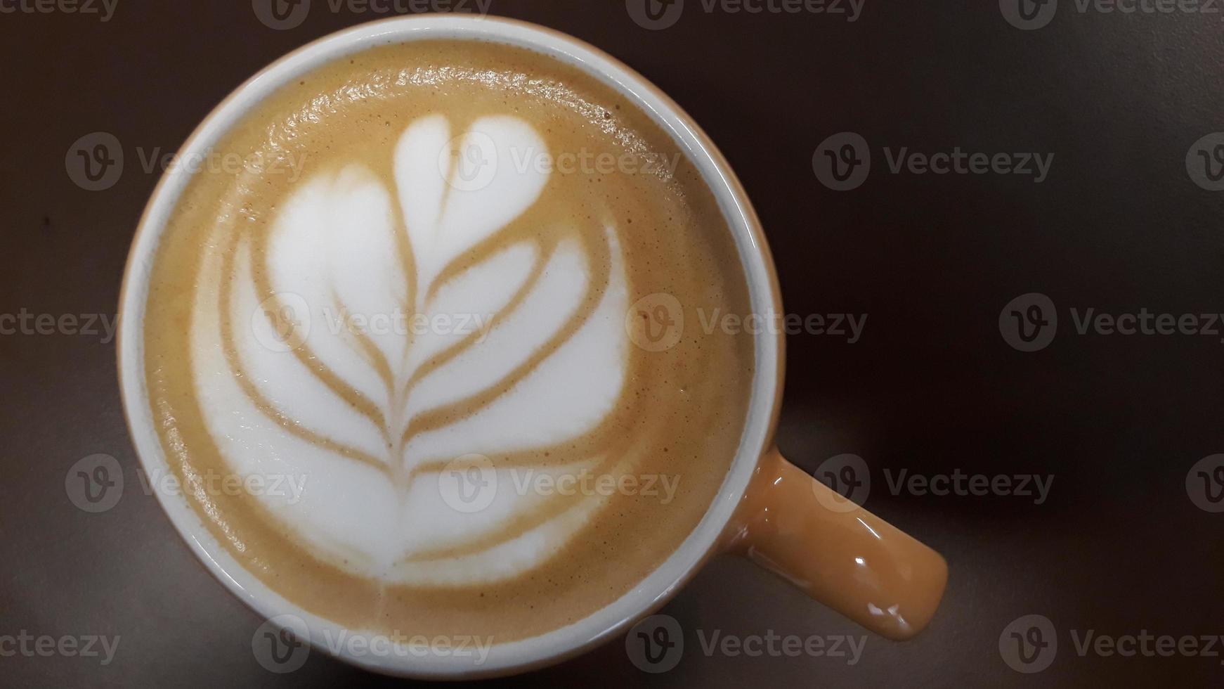 topp se varm kaffe latte cappuccino kopp topp med kvinna hand på brun bakgrund med selektiv fokus foto