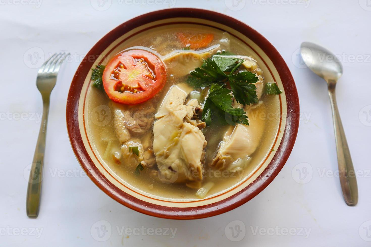 kyckling soppa eras med grönsaker, tomater, selleri i en skål, sked och gaffel. med svart bakgrund foto