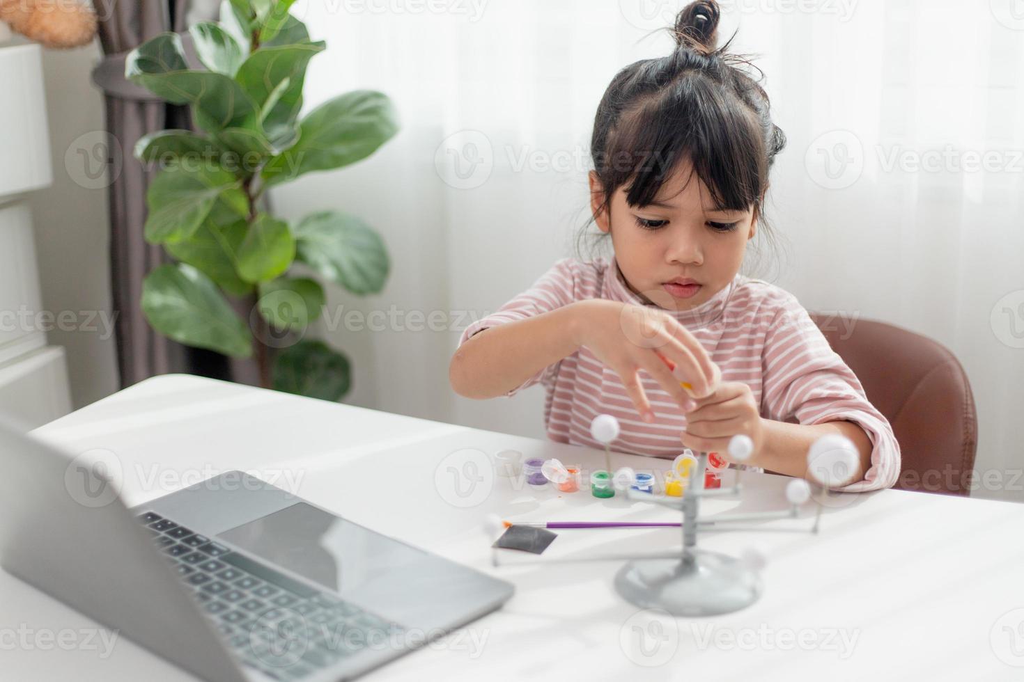 asiatisk liten flicka studier de sol- systemet i geografi klass. ser på de skala modell av planeter foto