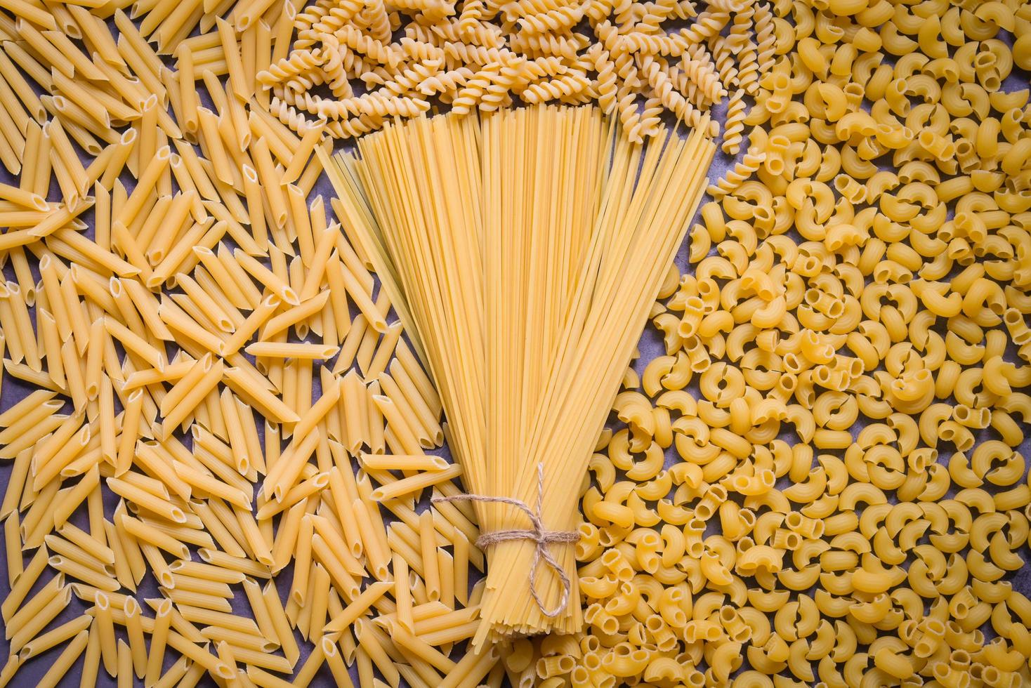 rå pasta olika typer av okokt pasta makaroner spaghetti och spaghetti på trä, italiensk mat kulinariska begrepp, samling av annorlunda rå pasta på matlagning tabell för matlagning mat foto