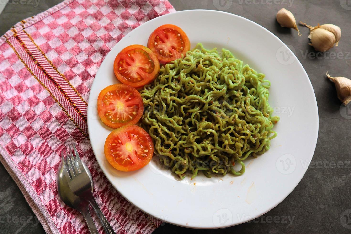 grön spaghetti, eller spenat pasta , zucchini rå vegan pasta dopp, och tomater på tallrik. foto