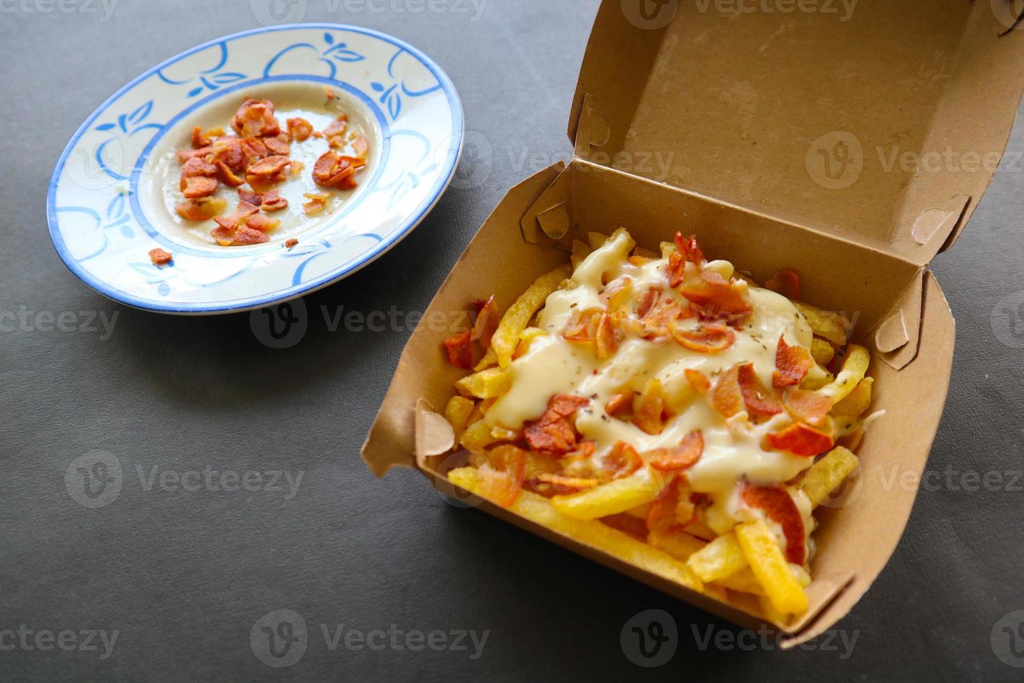 friterad frites med med smält Cheddarost ost eller friterad ost med garnering korv skivor på låda foto