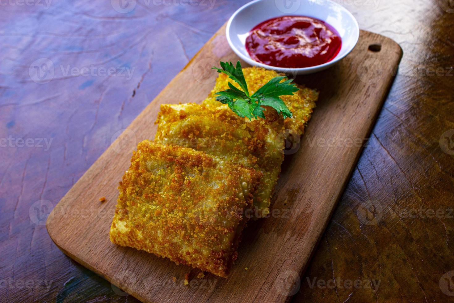 friterad risoles eller risol mayo är indonesiska snacks. tycka om coxinha de galinha. eras med chili sås, selleri på trä styrelse foto