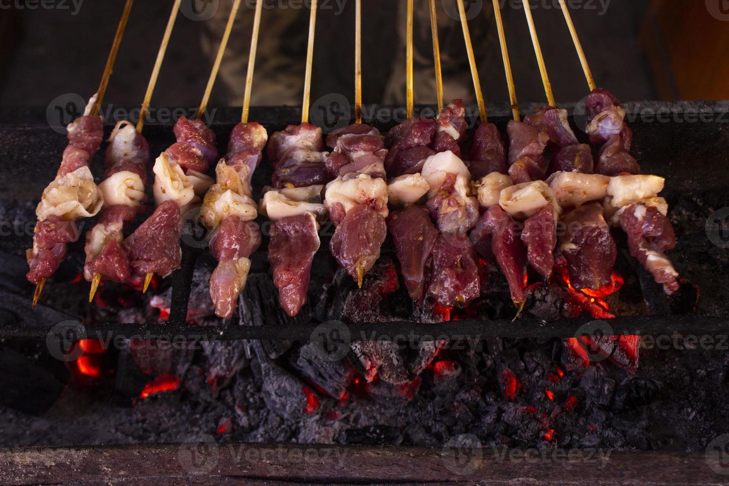 sate kambing eller satay get, lamm, lamm eller kött get satay med träkol ingrediens på röd brand grillning förbi människor. traditionell satay från yogyakarta, java, indonesien matlagning satay foto