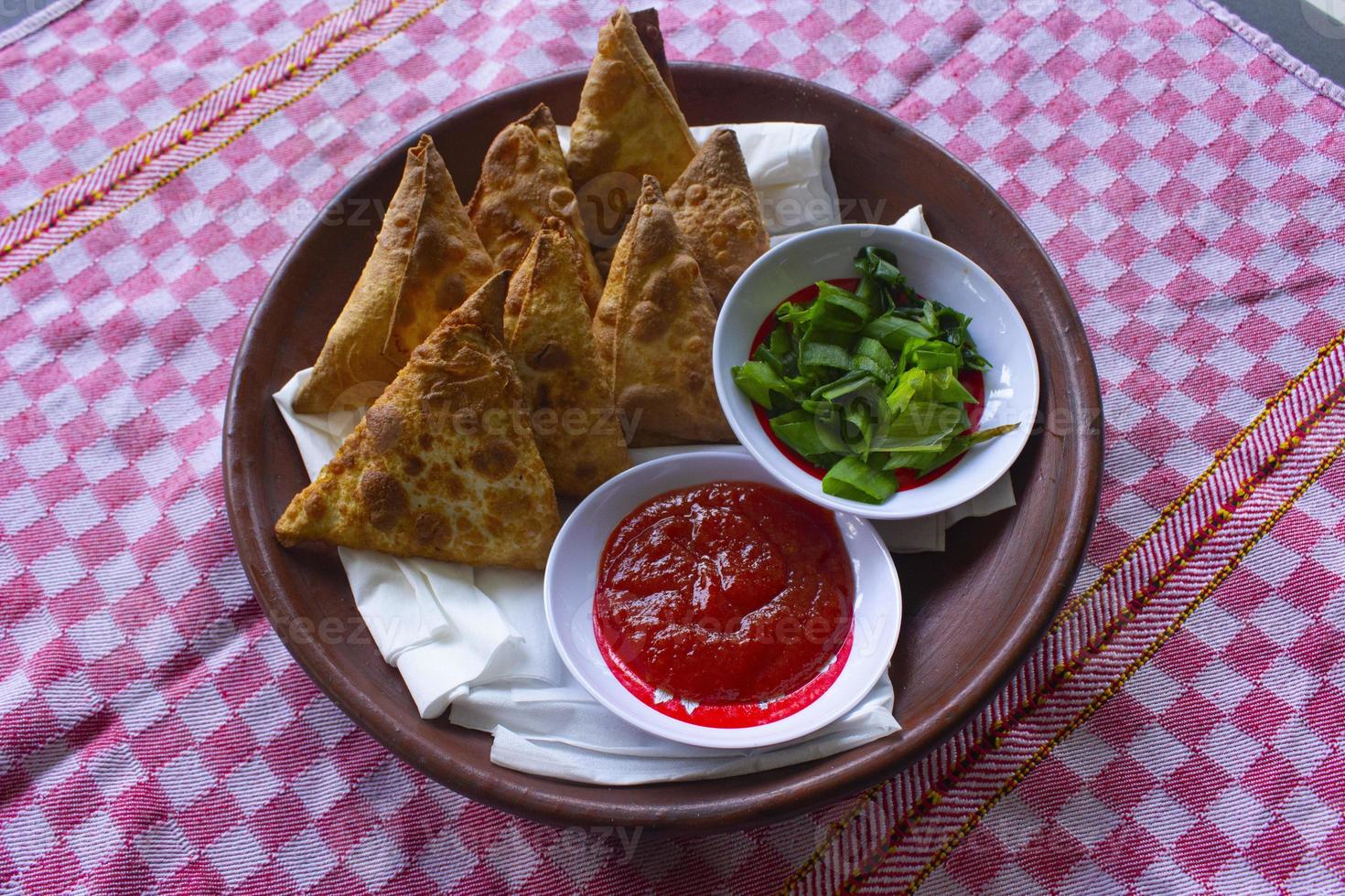 samosa, Samsa eller somsa är triangel- friterad bakverk eller bakverk eras med tomat sås och purjolök skiva, på svart bakgrund foto