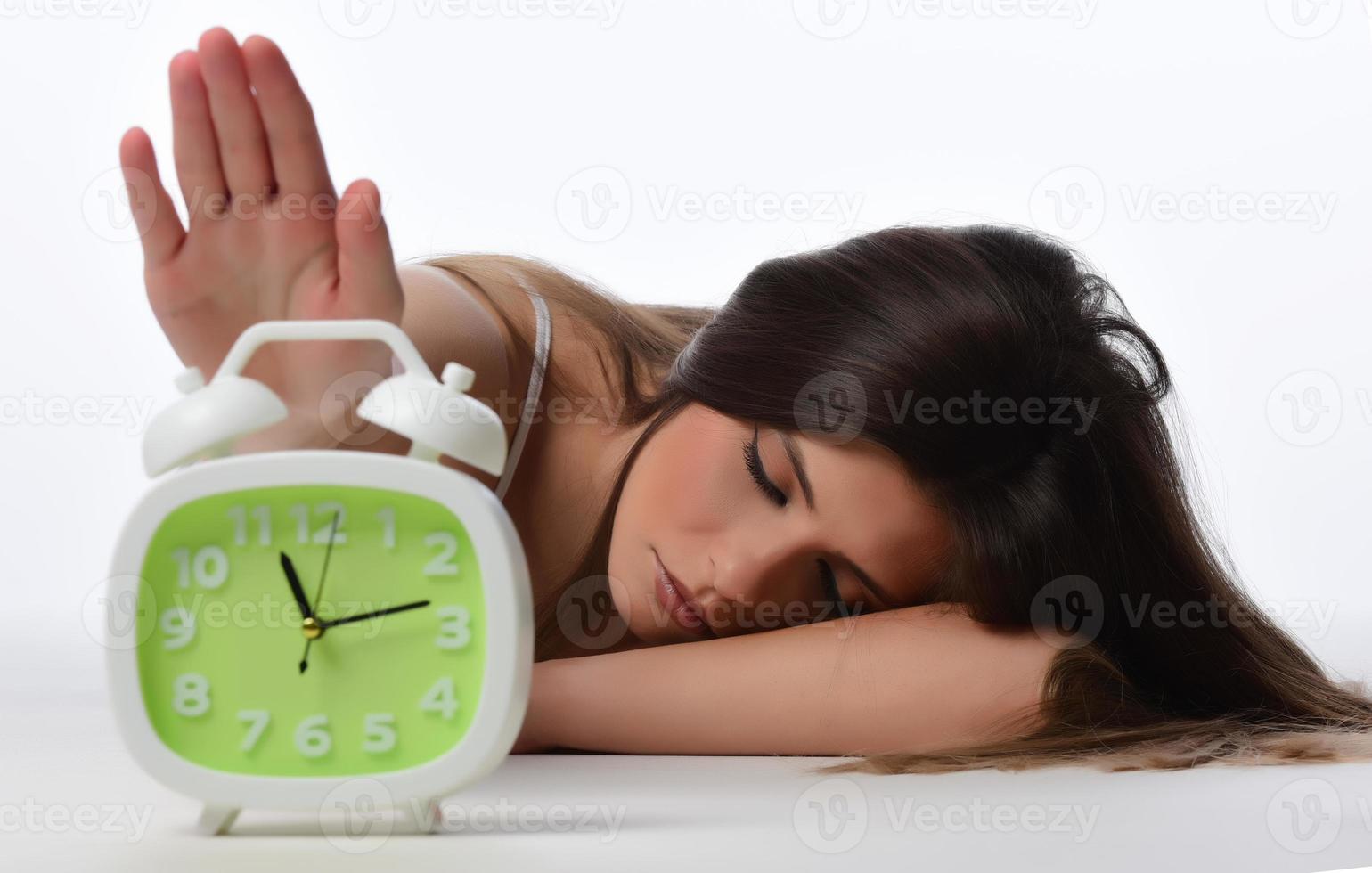 skön sovande kvinna vilar i säng med larm klocka redo till vakna henne i de morgon. foto